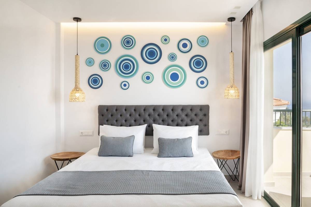 Schlafzimmer mit Bett, grauem Kopfteil und dekorativen blauen und grünen Kreisen an der Wand.