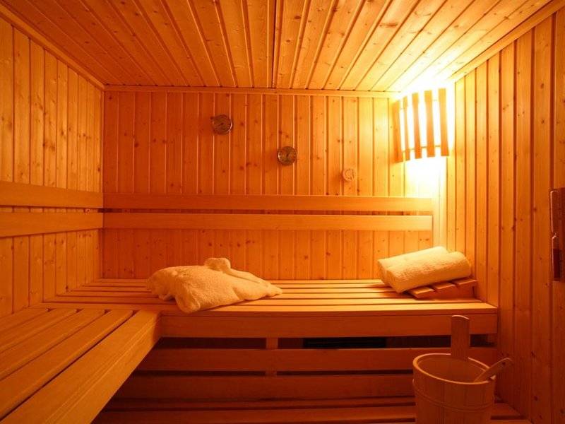 Holzsauna im Naxos Resort Beach Hotel mit heller Beleuchtung und Holzbänken.