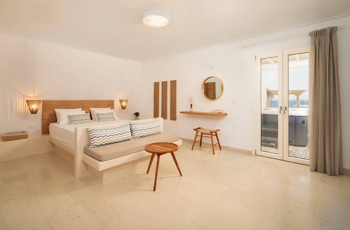 Ein modernes Schlafzimmer im Proteas Hotel mit einem Bett, Nachttischen und einem Blick auf das Meer.