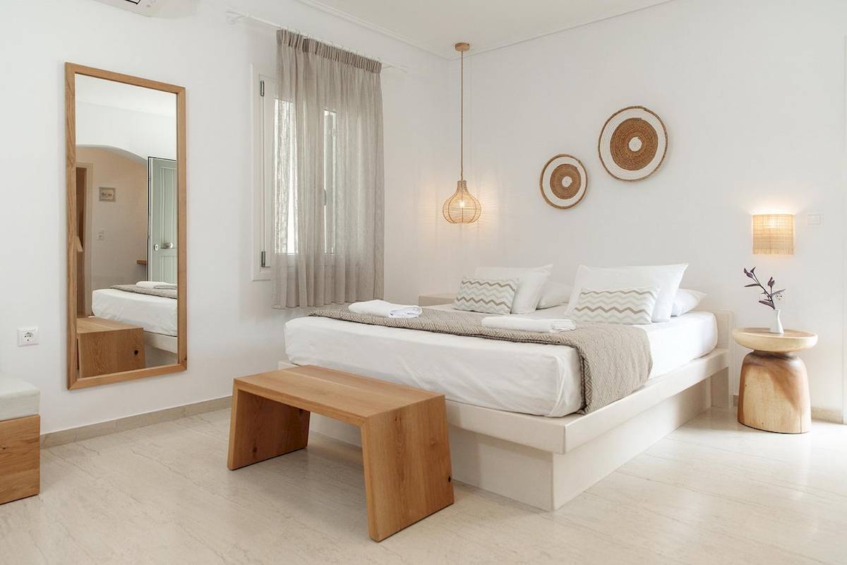 Schlafzimmer im Proteas Hotel & Suites mit weißen Wänden, Bett, Spiegel und Nachttisch