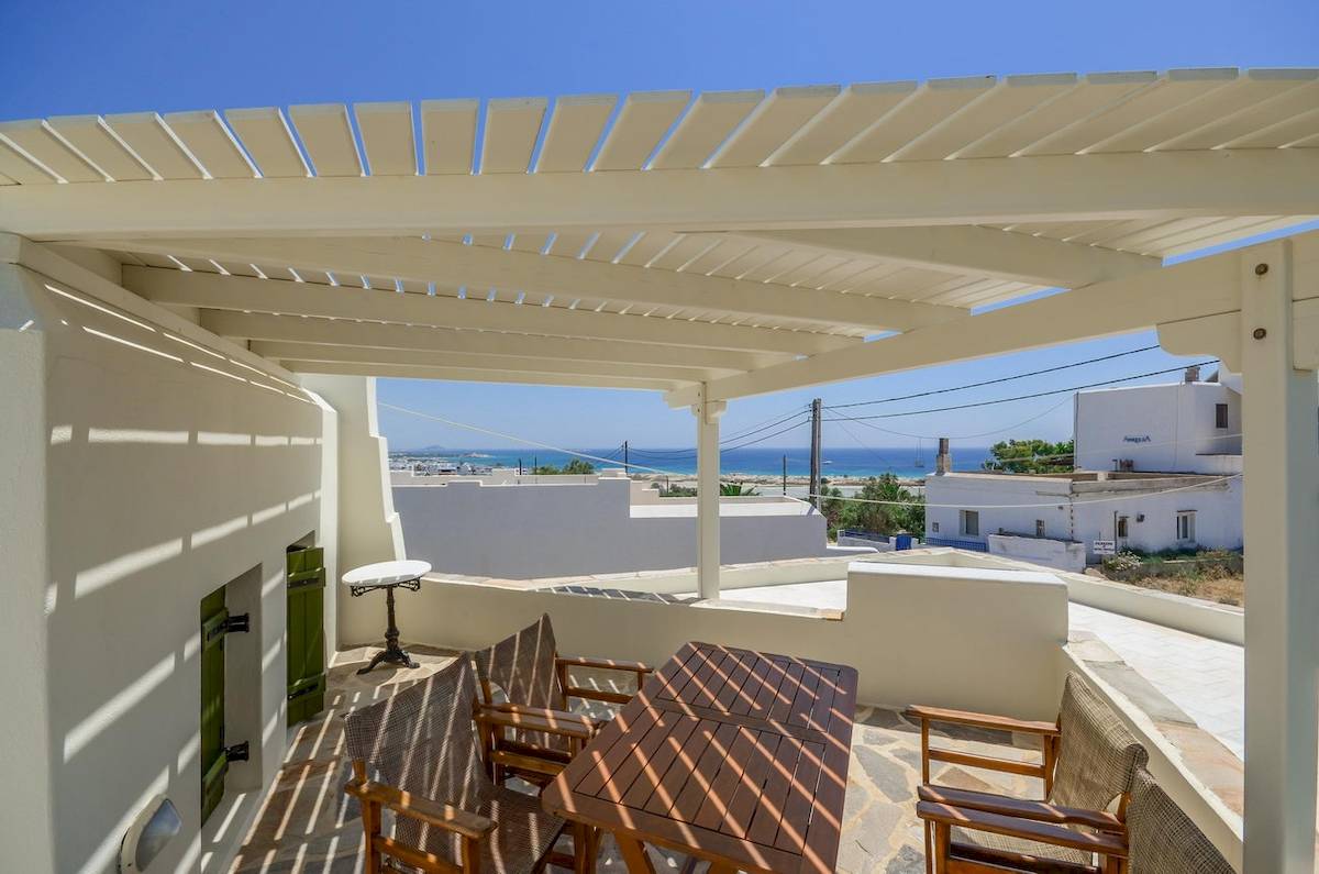 Terrasse im Proteas Hotel & Suites mit Meerblick und weißen Gebäuden im Hintergrund.