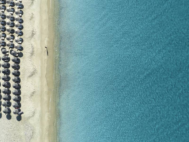 Luftaufnahme des Lagos Mare Hotels mit vielen Sonnenschirmen am Strand und blauem Wasser.