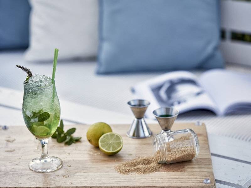 Ein grüner Cocktail mit Minze und Limette auf einem Holzschneidebrett.