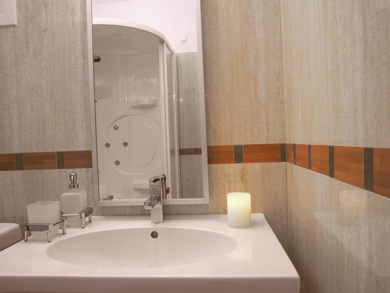 Badezimmer im Lagos Mare Hotel mit weißem Waschbecken und Spiegel.