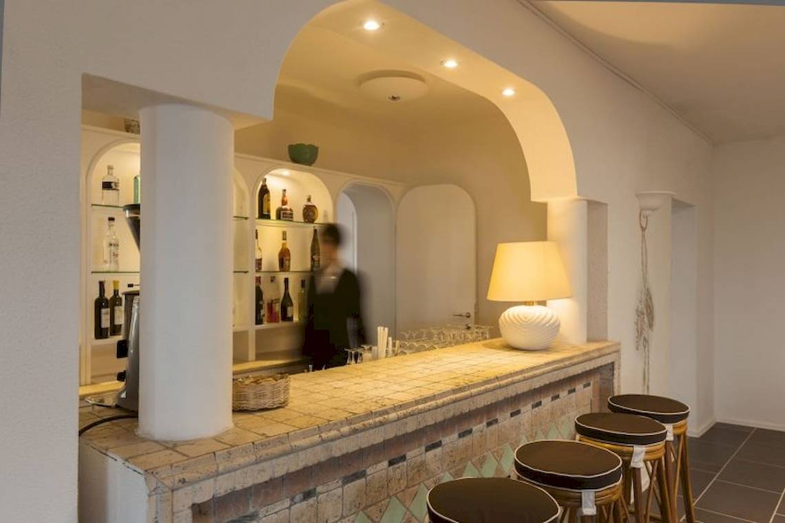 Innenansicht der Bar im Mare Pineta Hotel mit Theke, Stühlen und Lampen.