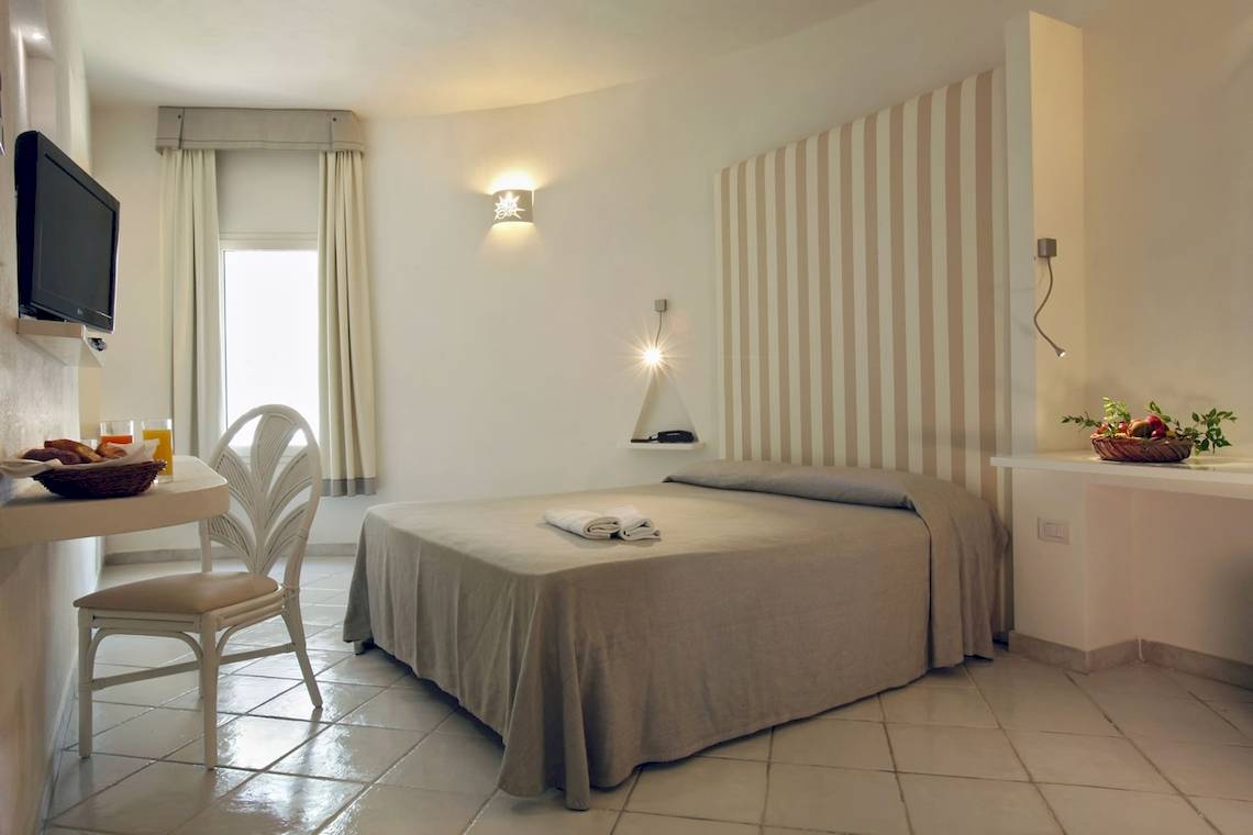 Hotelzimmer im Mare Pineta Hotel mit Bett, Tisch, Fernseher und Obstkorb.