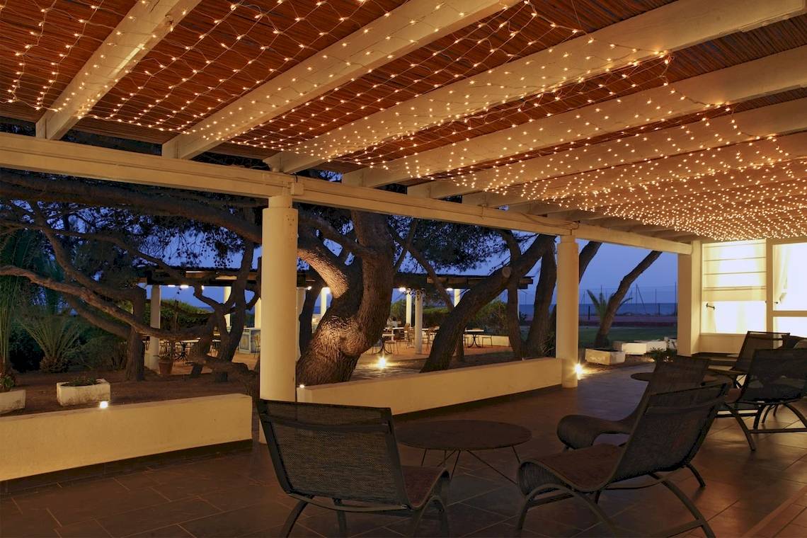 Terrasse im Mare Pineta Hotel bei Nacht mit beleuchteten Lampen und Möbeln.