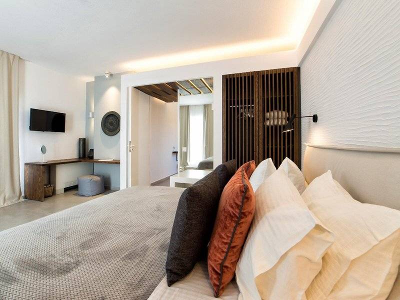 Schlafzimmer im Paros Agnanti Resort & Spa mit Bett, Fernseher und Deko-Elementen.