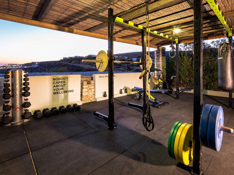 Fitnessbereich im Paros Agnanti Resort & Spa mit verschiedenen Geräten und einer Wand mit Zitat.