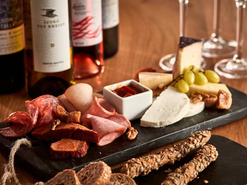 Poseidon of Paros Hotel & Spa Speiseplatte mit Käse, Fleisch, Wein und Brot.