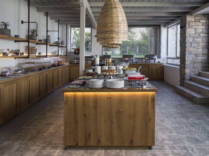 Frühstücksbereich im Poseidon of Paros Hotel & Spa mit Buffet und Holzmöbeln.