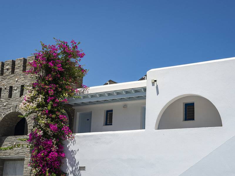 Außenansicht des Pyrgaki Hotels mit weißen Wänden und blühenden Bougainvillea-Pflanzen.