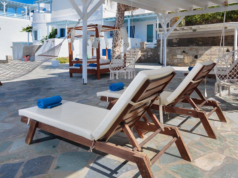Lounge-Stühle und Hängematten im Pyrgaki Hotel mit Blick auf ein weißes Gebäude.
