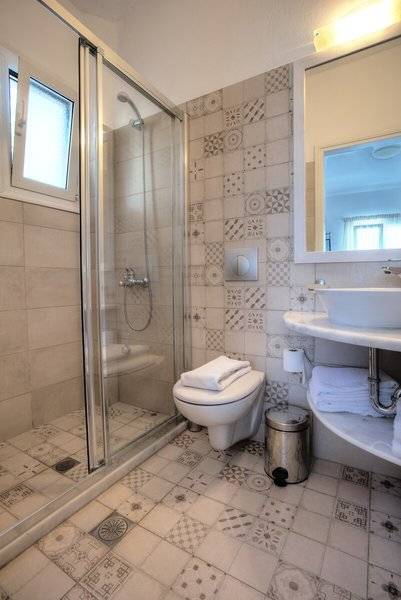 Badezimmer im Pyrgaki Hotel mit einer Glasdusche, einem Waschbecken und einem Spiegel.