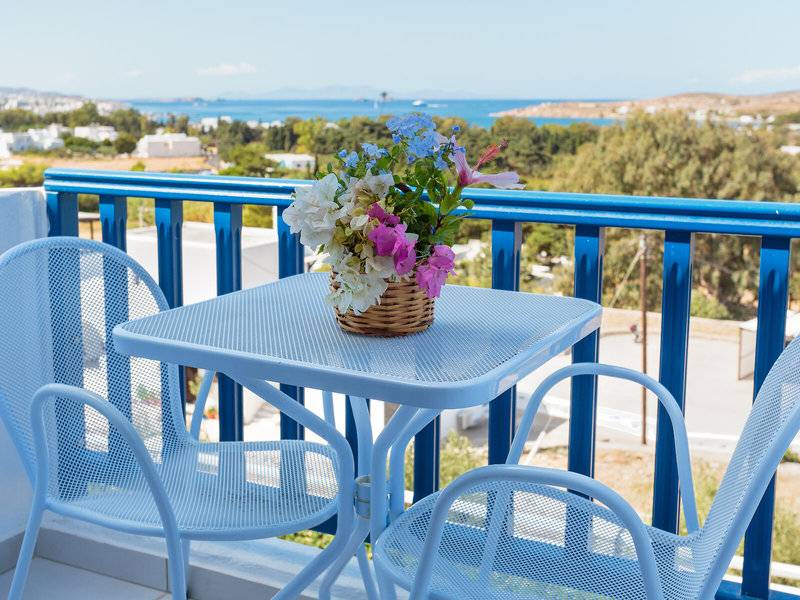 Ein Balkon mit Blumen auf einem Tisch und zwei Sesseln im Pyrgaki Hotel.