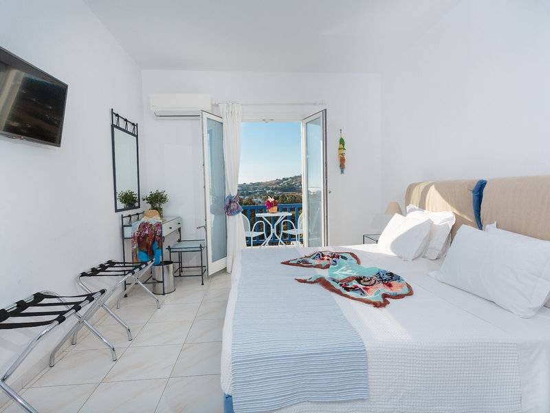 Schlafzimmer im Pyrgaki Hotel mit Blick auf einen Balkon und eine Terrasse.