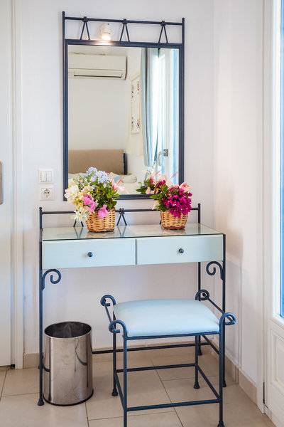 Kleiner Tisch mit Spiegel im Zimmer des Pyrgaki Hotels mit Blumen in Körben.