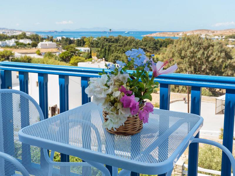 Balkon mit blauem Geländer und Blick auf das Meer, Blumen in einem Korb auf einem Tisch