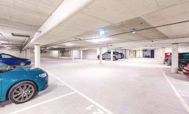 Unterirdischer Parkplatz im Four Elements Hotel Amsterdam mit mehreren geparkten Autos.