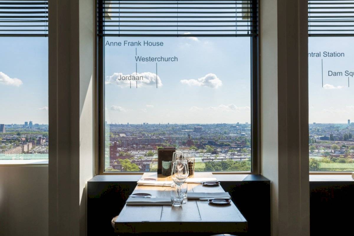 Ein Tisch in einem Restaurant mit Blick auf die Stadt, an dem eine Tischkarte und leere Weingläser stehen.