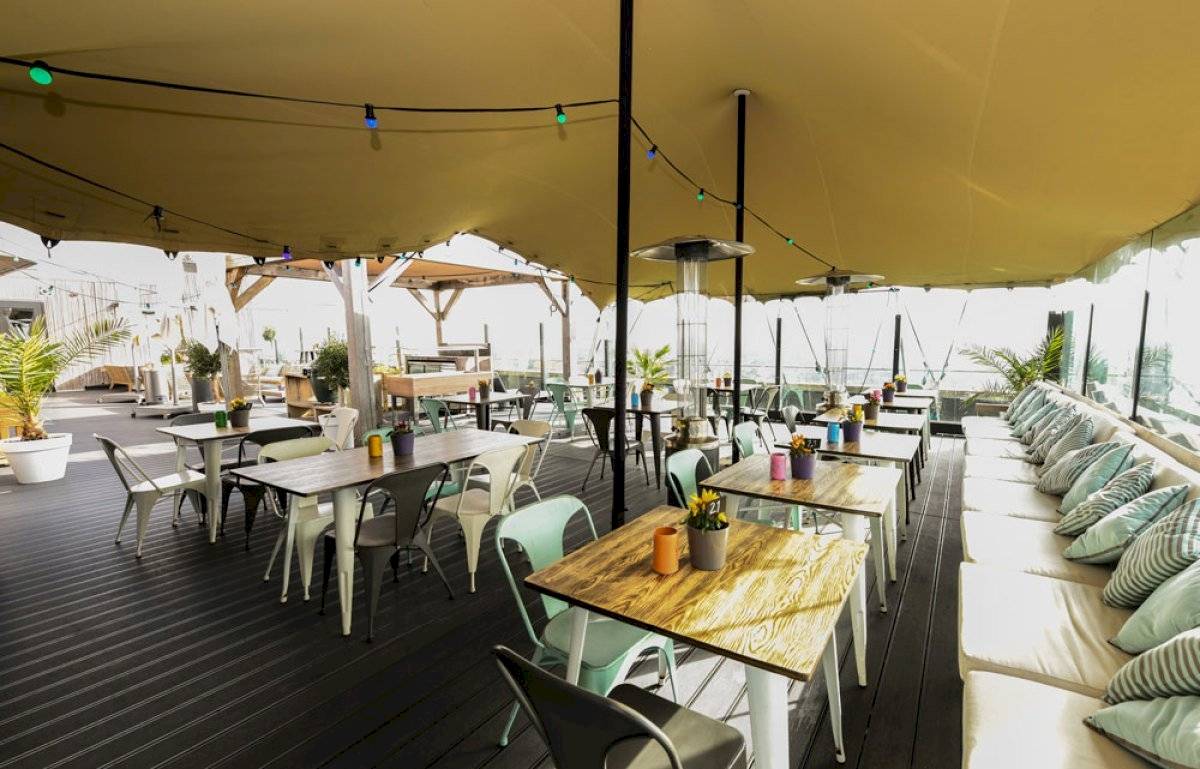 Terrasse des Leonardo Hotel Amsterdam Rembrandtpark mit Tischen und Stühlen unter einem Zeltdach.