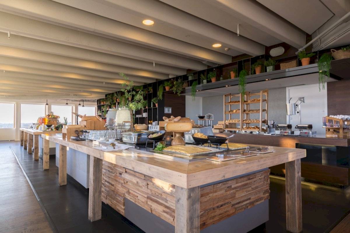 Frühstücksbuffet im Leonardo Hotel Amsterdam Rembrandtpark mit verschiedenen Gerichten und Holztischen.