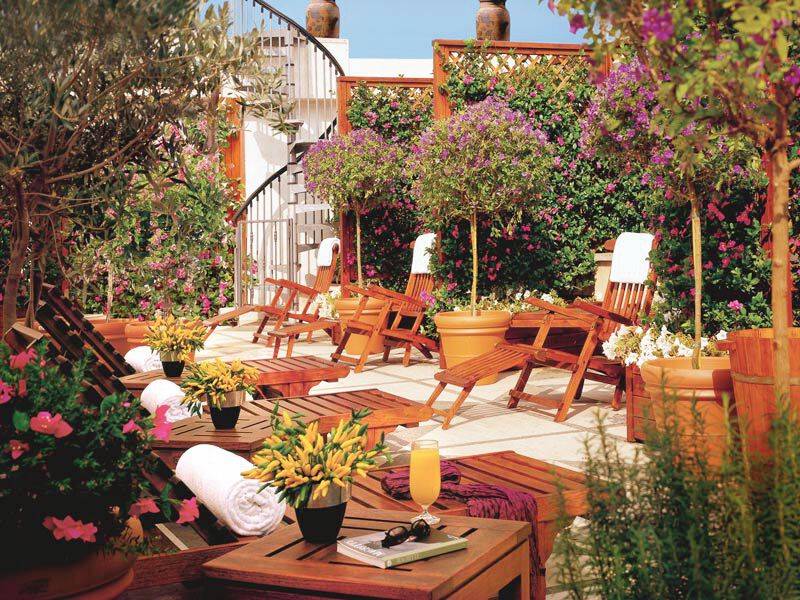 Terrasse des Dei Mellini Hotels mit Holzliegen, Pflanzen und einem Glas Orangensaft