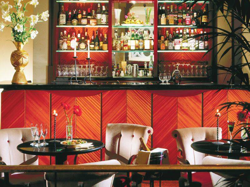 Innenansicht der Bar des Dei Mellini Hotels mit gefüllten Gläsern, Kerzen und einem Tisch mit Essen.