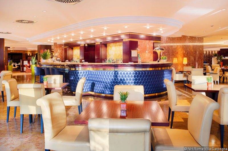 Hotelbar des NH Roma Villa Carpegna mit blauer Theke und weißen Lederstühlen.