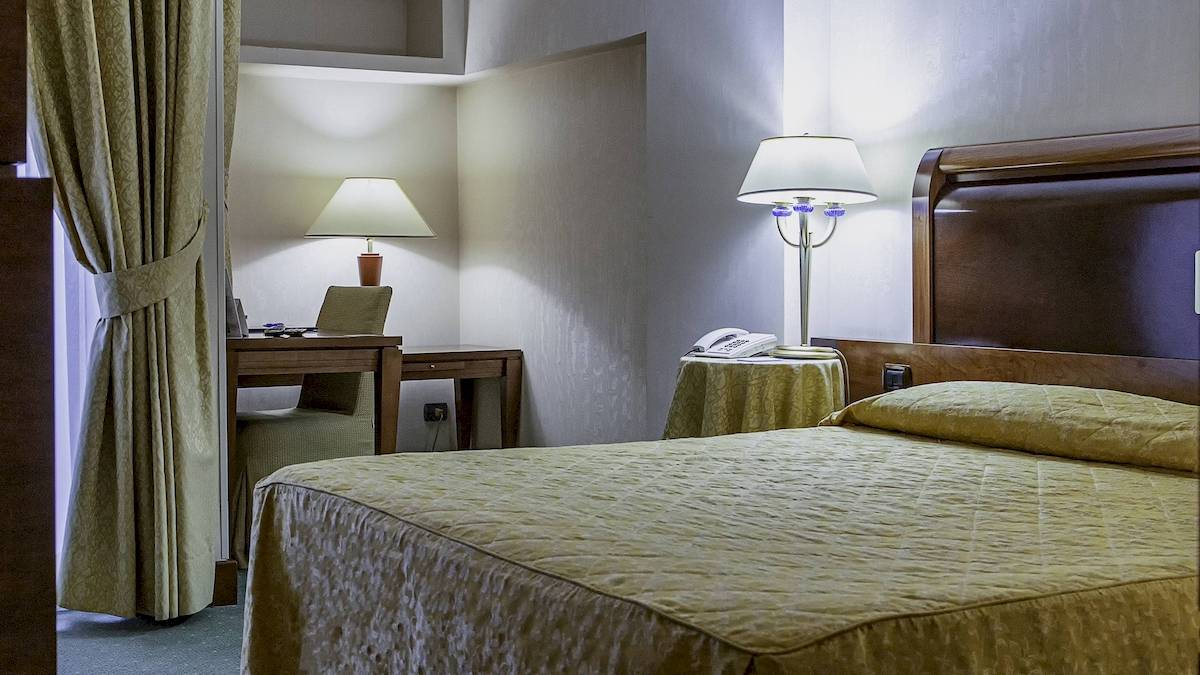 Schlafzimmer im Pineta Palace Hotel mit Bett, Schreibtisch und Lampen.
