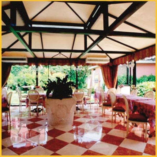 Tre Archi Hotel Innenbereich mit Terrasse, rot-weißes Schachbrettmuster auf dem Boden, Möbel und Pflanzen.