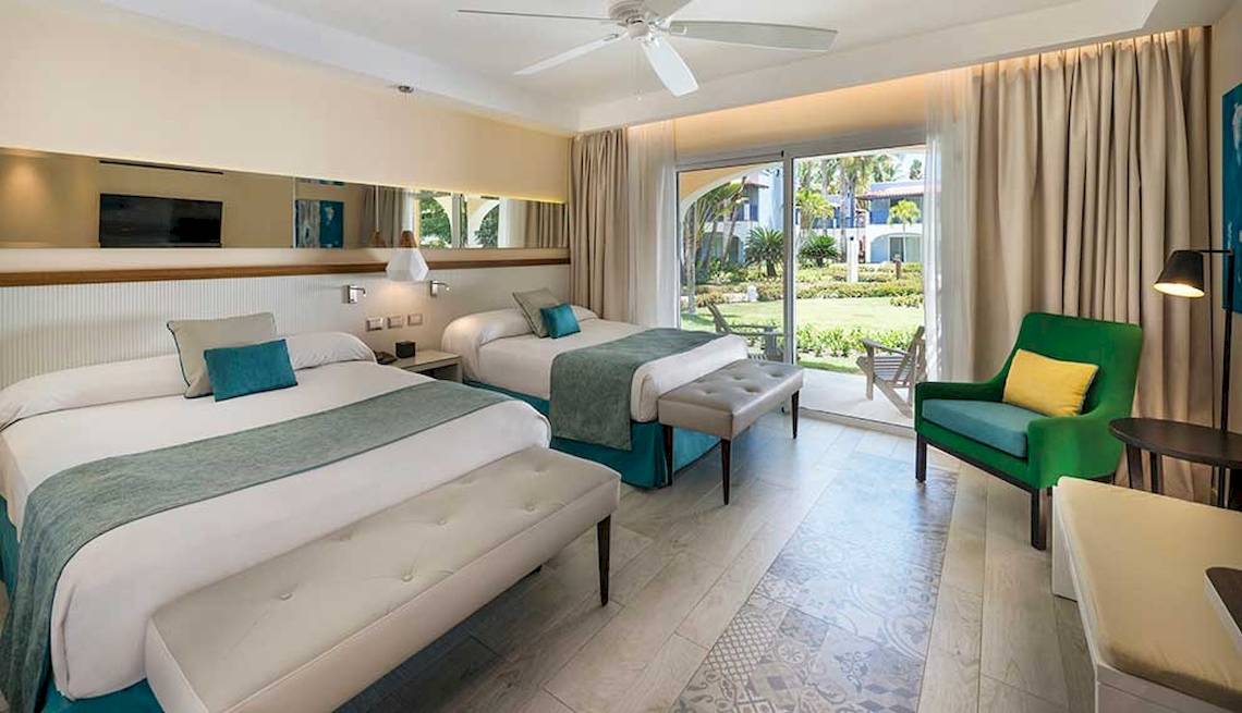 Doppelzimmer im Catalonia Bayahibe Hotel mit zwei Betten, großer Terrasse und Gartenblick.