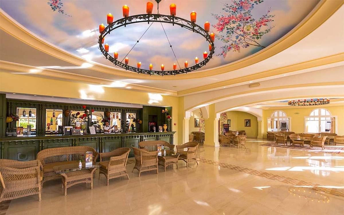 Lobby des Medina Belisaire & Thalasso Hotels mit einer gemusterten Decke, einer Theke und Rattanmöbeln.