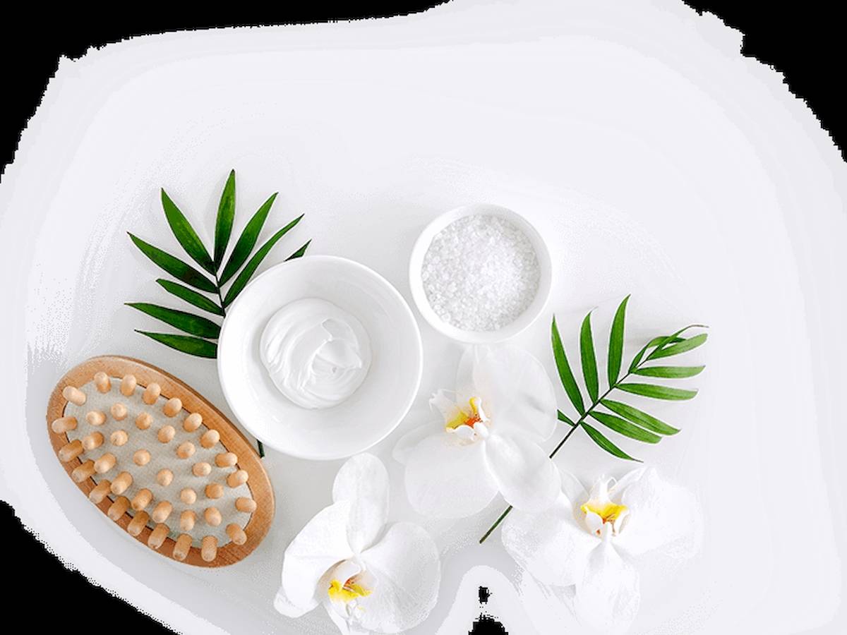 Gesichtspflegeprodukte wie eine Creme, Salz und Blüten auf weißem Hintergrund