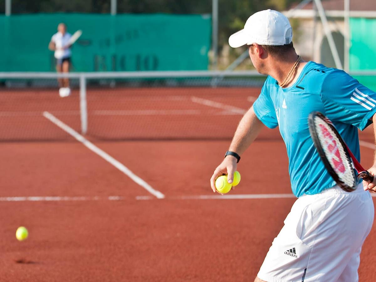 Tennisspieler spielt auf einem roten Tennisplatz während eines Matches.
