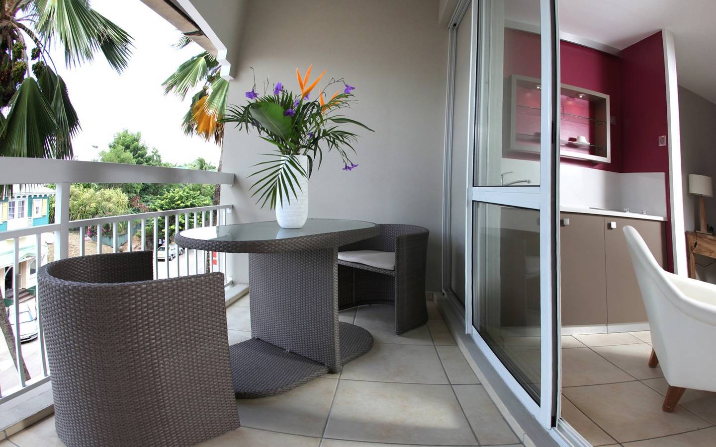 Ein Balkon des La Pagerie - Tropical Garden Hotel mit Tisch, Stühlen und einer Vase mit Blumen.
