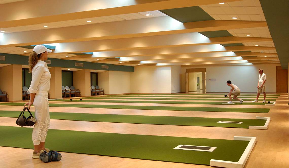 Innenansicht der Bowlingbahn im Constantinou Bros Athena Beach Hotel mit Spielern und Holzböden.