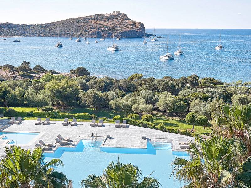 Aussicht auf den Poolbereich des Cape Sounio Grecotel Resorts mit vielen Liegestühlen und Booten im Meer