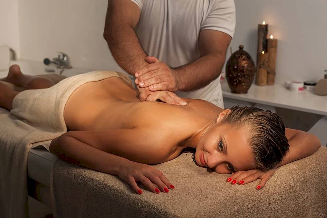 Frau, die eine Massage im Spa genießt, während ein Mann sie massiert