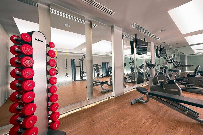 Fitnessbereich des Nema Design Hotels mit roten Gewichten und Spiegeln.
