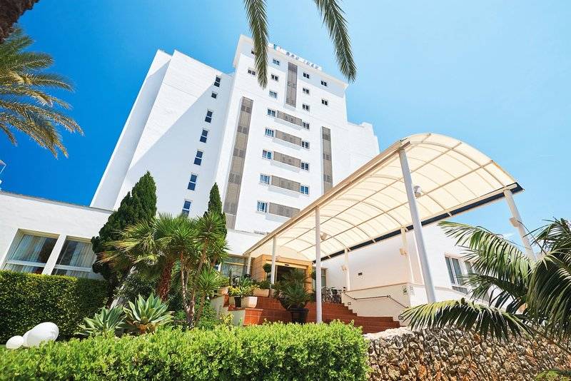 Außenansicht des Hipotels Don Juan Hotels mit weißem Gebäude und tropischen Pflanzen.