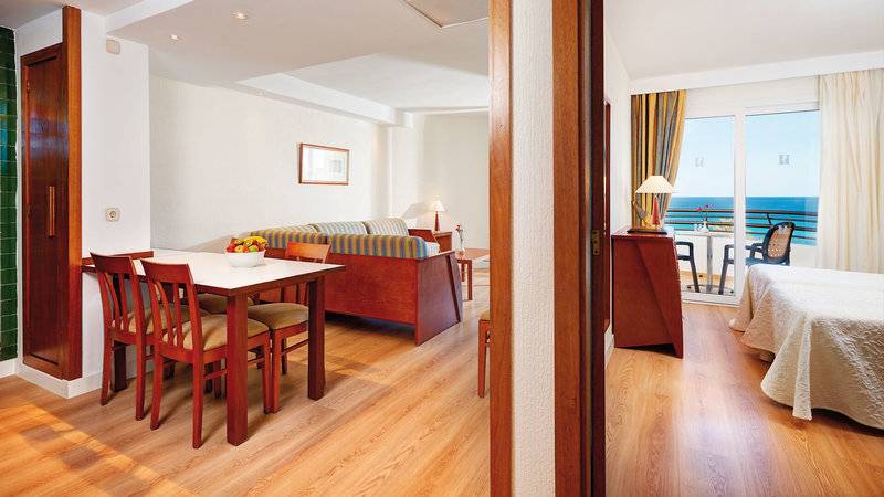 Innenansicht des Hipotels Dunas Cala Millor Hotels mit Esstisch, Sofa und Meerblick