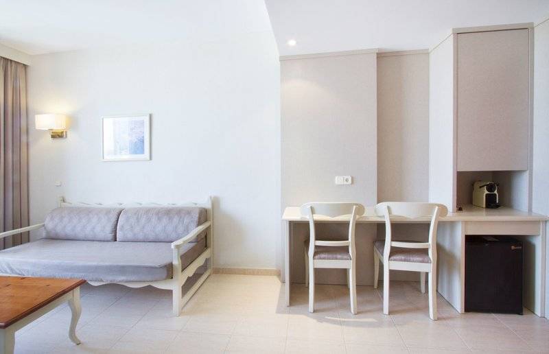 Hotelzimmer im Bakour Garbi Cala Millor mit einem Sofa, Schreibtisch und zwei Stühlen.