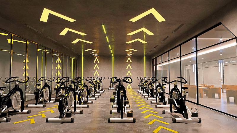 Fitnessstudio im Aldiana Club Side Beach mit vielen Spinrädern und gelben Lichtakzenten an der Decke.