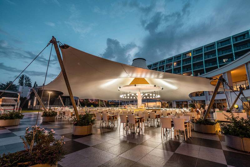 Alfresco-Restaurant des Green Nature Diamond Hotels bei Nacht mit einem großen Dach und vielen Tischen und Stühlen.