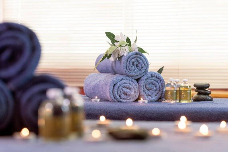 Spa-Behandlungsbereich im Sherwood Exclusive Kemer Hotel mit Handtüchern, Kerzen und ätherischen Ölen.