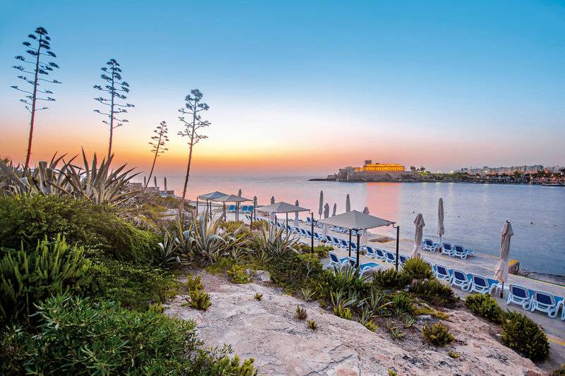 Sonnenuntergang am Strand des Corinthia St George's Bay Hotels mit Blick auf das Meer und die Stadt.