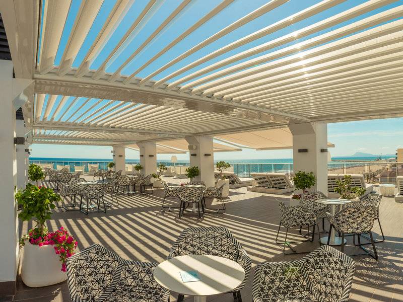 Terrasse des RH Bayren & Spa mit Sonnenliegen und Sonnenschirmen am Meer