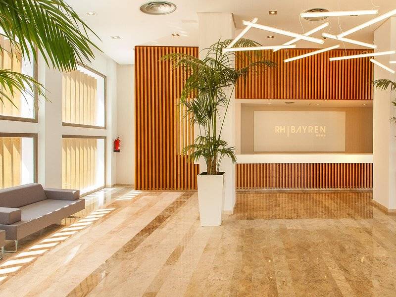 Hotellobby des RH Bayren & Spa mit modernem Design, großen Pflanzen und warmem Licht.