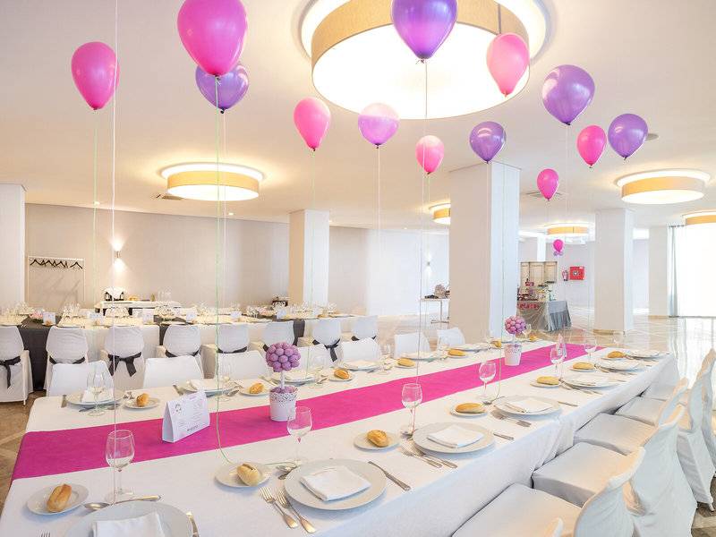 Bankettsaal im RH Bayren & Spa mit mehreren pinken und lilafarbenen Ballons, gedecktem Tisch und weißen Stühlen.